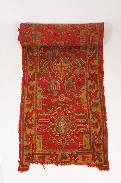 Appraisal: A TURKEY RED GROUND RUNNER with geometric medallions within a