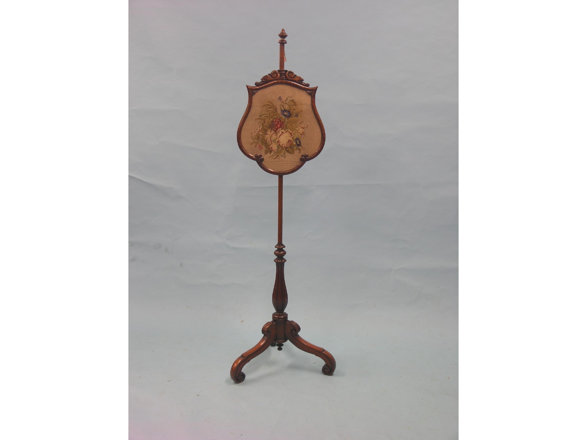 Appraisal: A Victorian mahogany pole-screen cartouche-shape screen with glazed floral petit-point