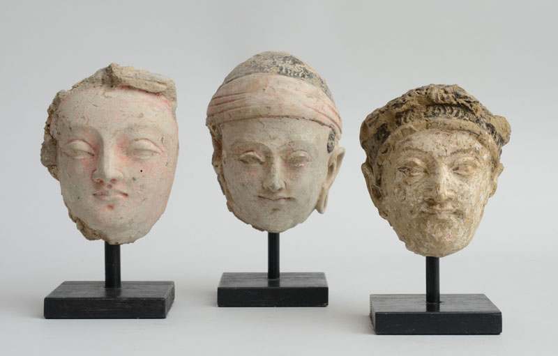 Appraisal: THREE GANDHARAN POLYCHROME CLAY MALE HEADS Each wearing scarf headdress