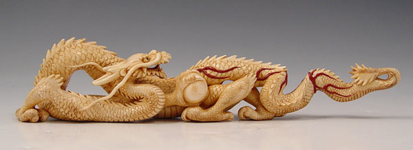 Appraisal: CARVED IVORY DRAGON WITH BALL Asian carved dragon with painted