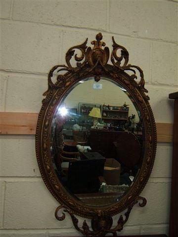 Appraisal: A gilt framed hanging oval wall mirror with scrolling crest