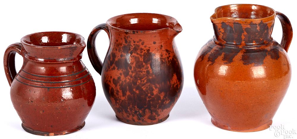 Appraisal: Three Pennsylvania redware pitchers Three Pennsylvania redware pitchers th c