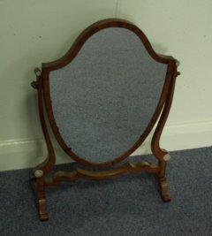 Appraisal: A mahogany shield shaped toilet mirror on S shaped supports