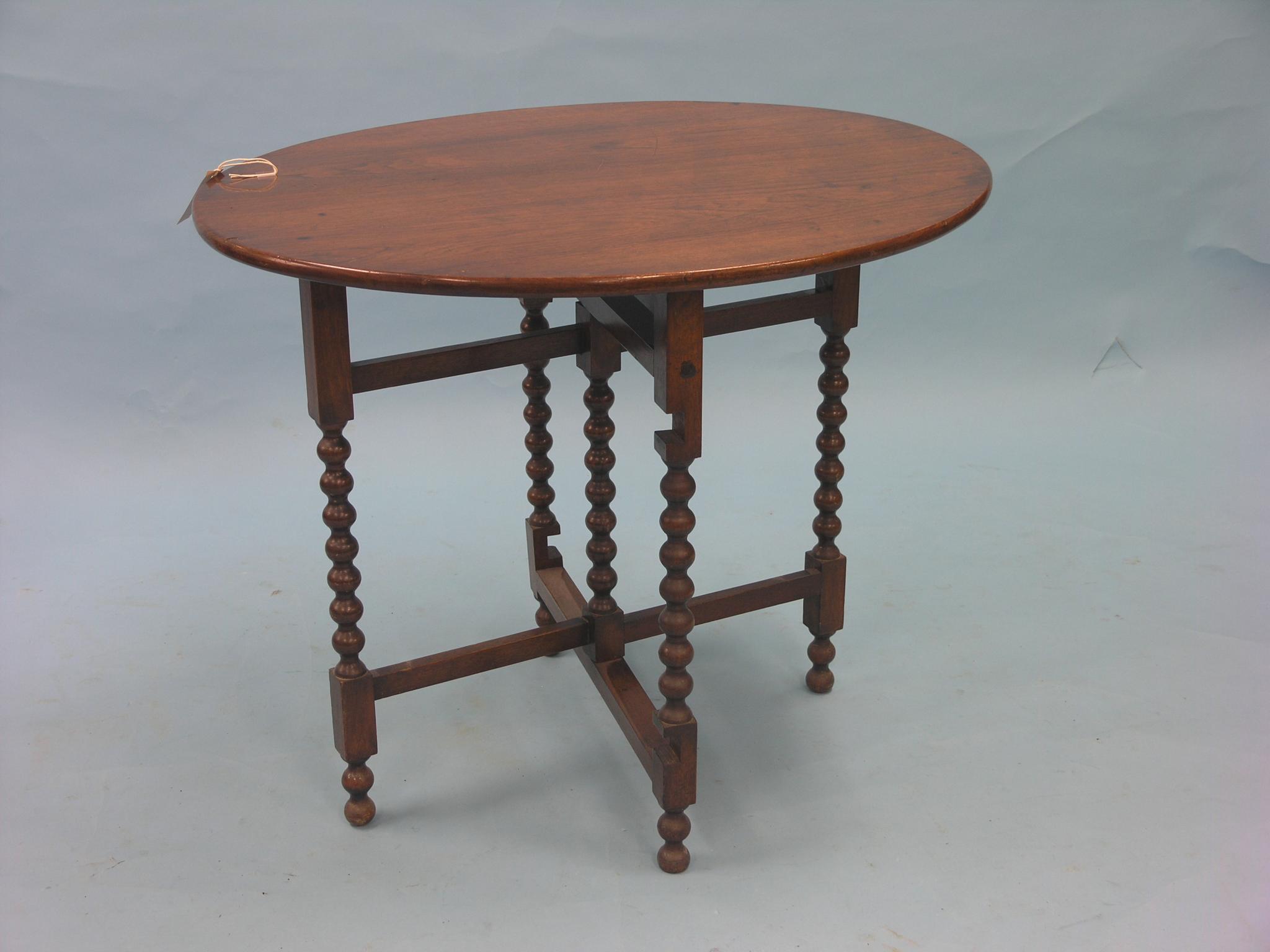 Appraisal: A solid walnut coaching table oval top on folding ball-turned