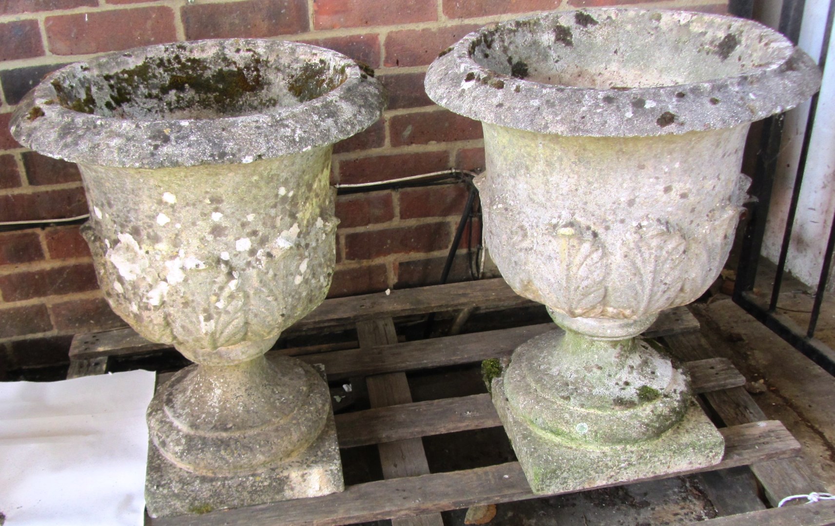 Appraisal: A pair of reconstituted stone garden urns with semi leaf