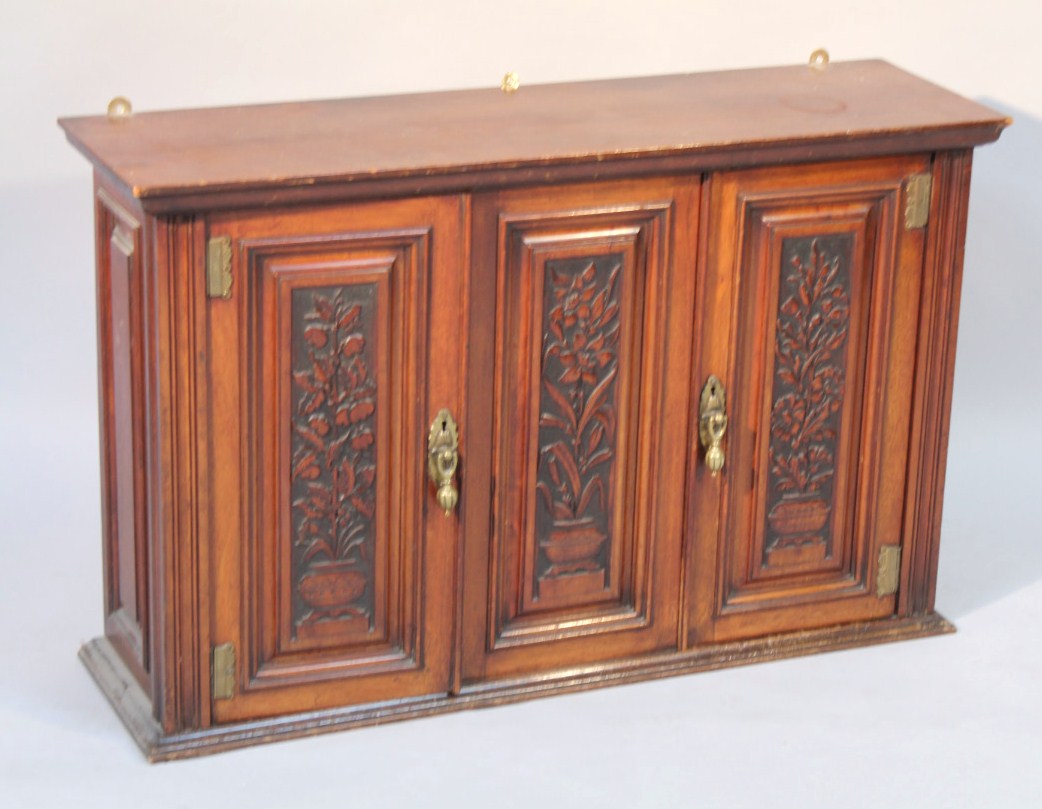 Appraisal: An Edwardian hanging cabinet with three heavily carved doors set