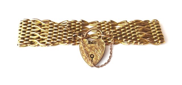 Appraisal: A gold crossover bar and oval link wide gate bracelet