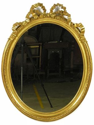 Appraisal: A giltwood and gesso oval wall mirror with a ribbon