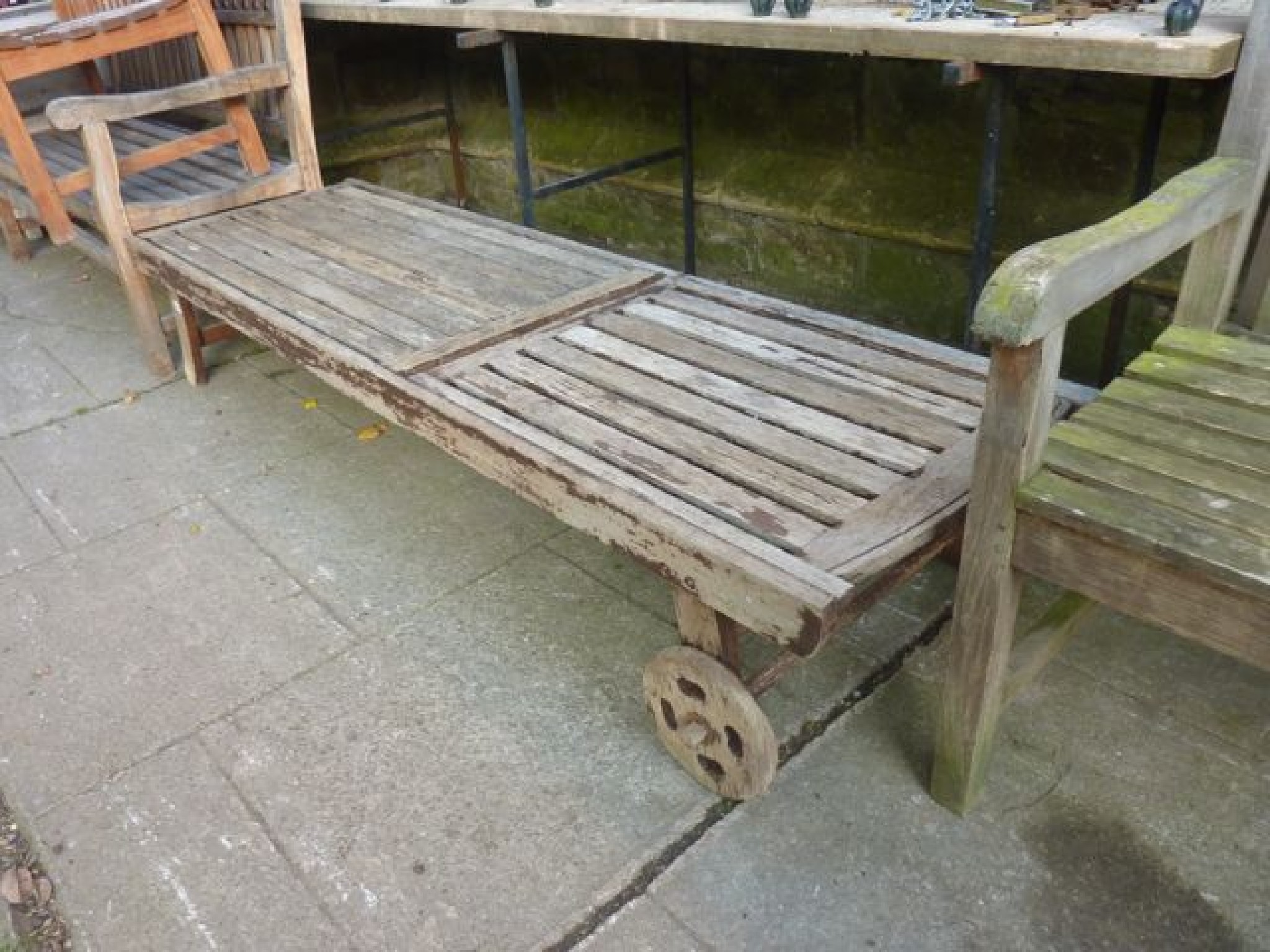 Appraisal: A weathered contemporary teak garden lounger with slatted seat and