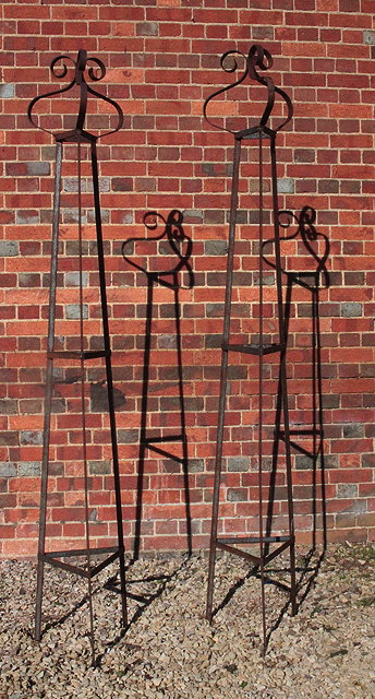 Appraisal: A PAIR OF WROUGHT IRON TRIANGULAR GARDEN OBELISKS with scrolling