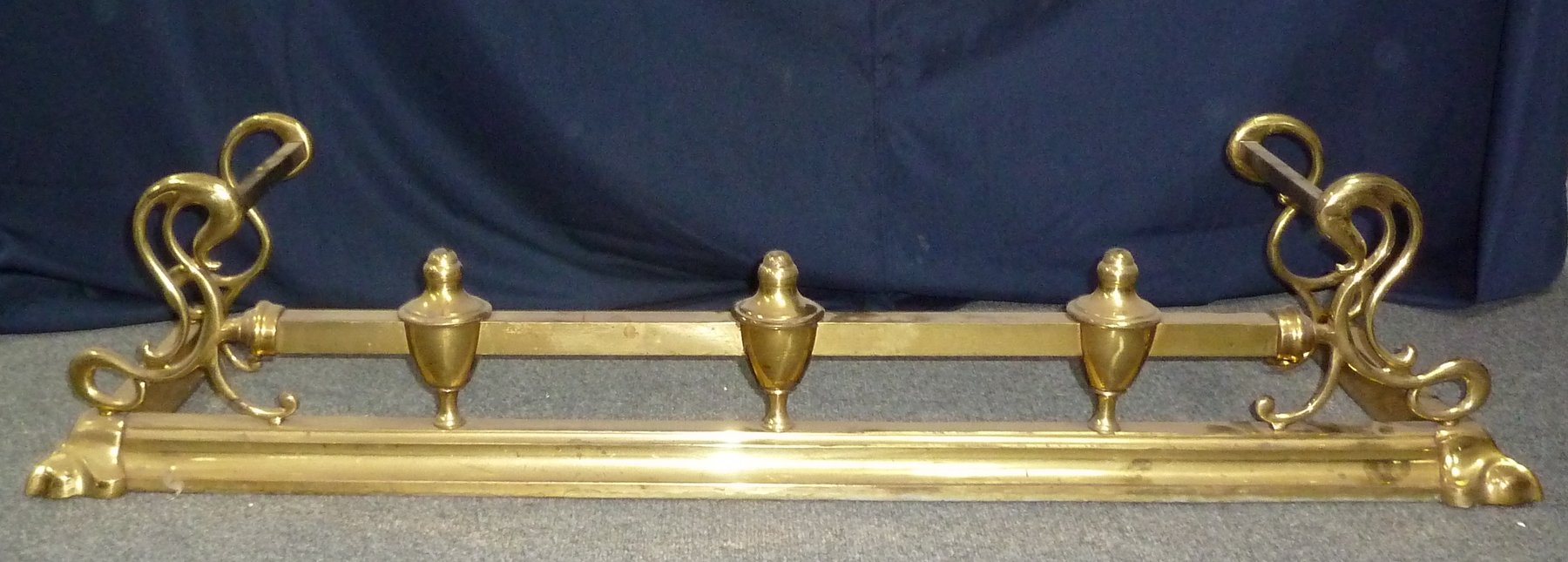 Appraisal: An Art Nouveau brass fender with scroll end supports cm