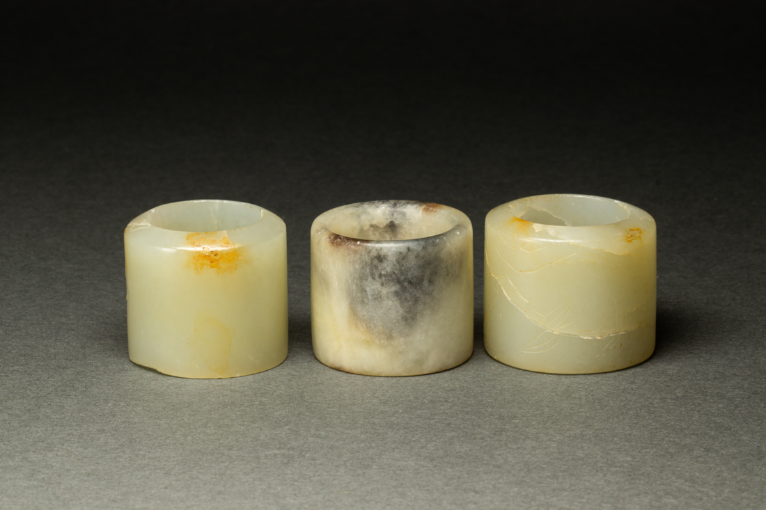 Appraisal: THREE WHITE JADE ARCHER'S RINGS Three celadon jade and hardstone