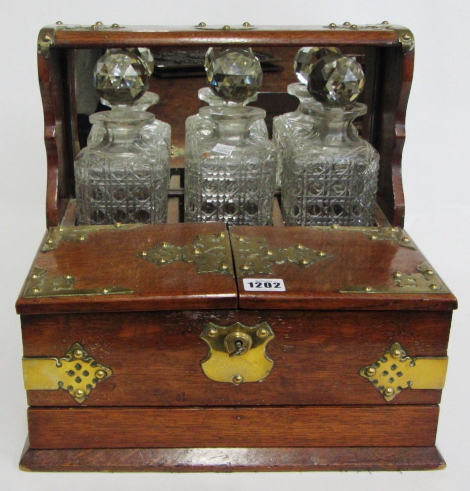 Appraisal: A Victorian oak and brass mounted three bottle tantalus with