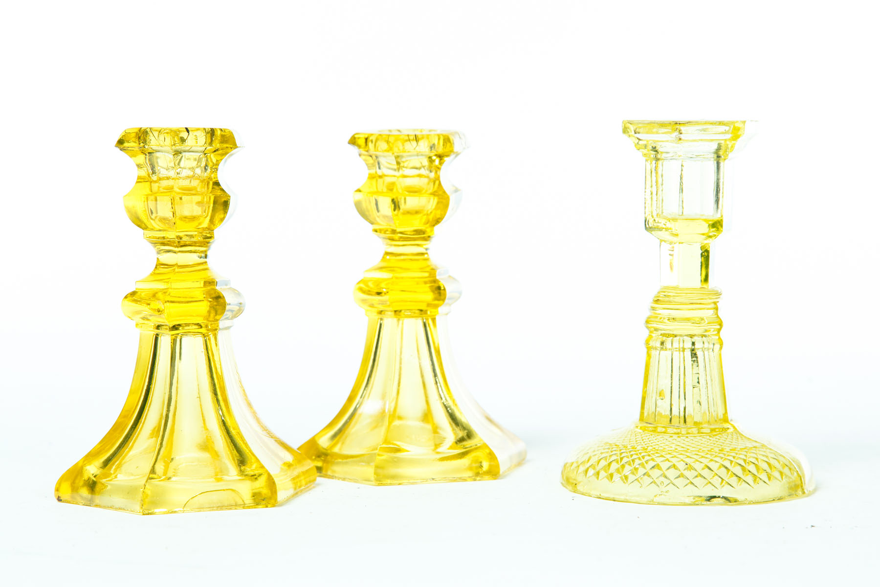 Appraisal: THREE GLASS CANDLESTICKS American mid th century Canary Pair of