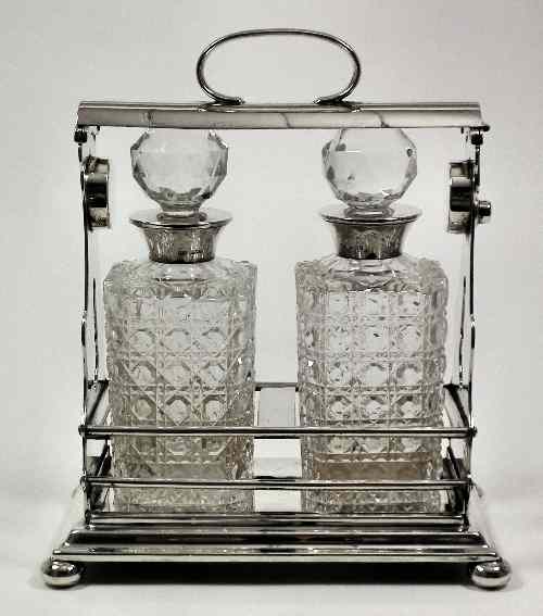 Appraisal: A silver plated rectangular two bottle tantalus with shaped and