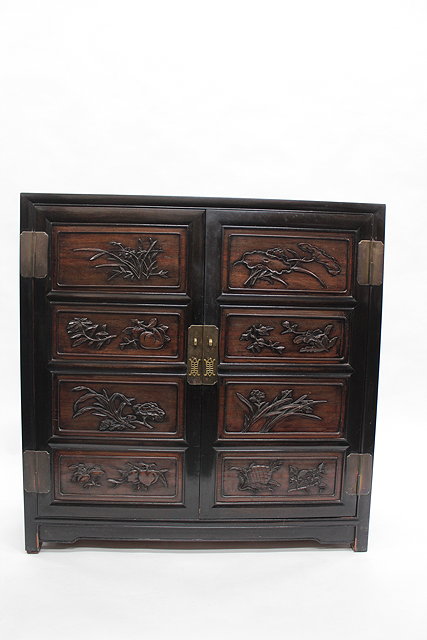 Appraisal: A CHINESE HARDWOOD SIDE CABINET the panelled doors carved with