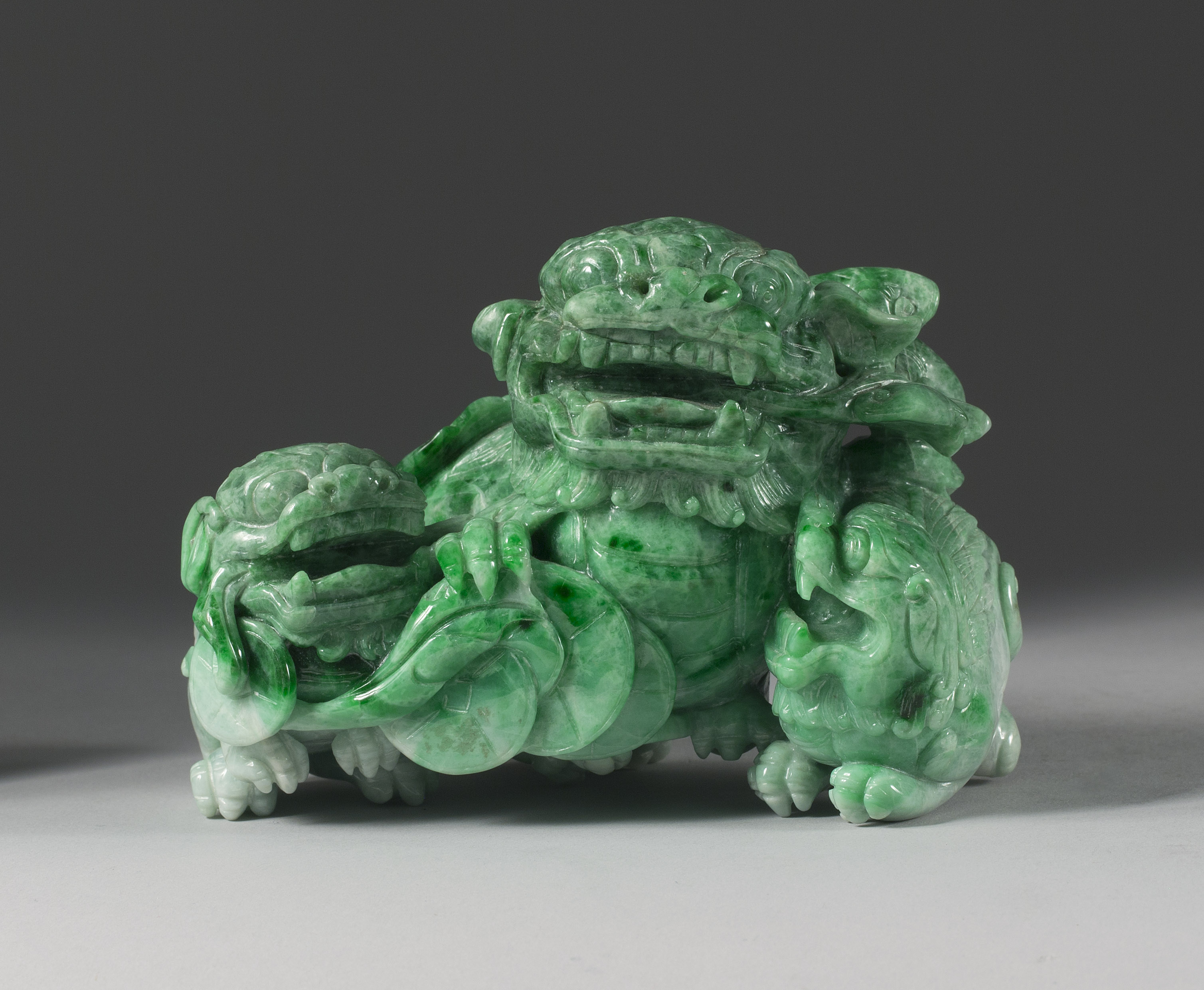 Appraisal: GREEN JADEITE CARVING th CenturyIn the form of three guardian