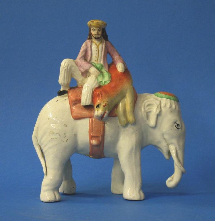 Appraisal: A STAFFORDSHIRE POTTERY ELEPHANT surmounted by a native bearer with