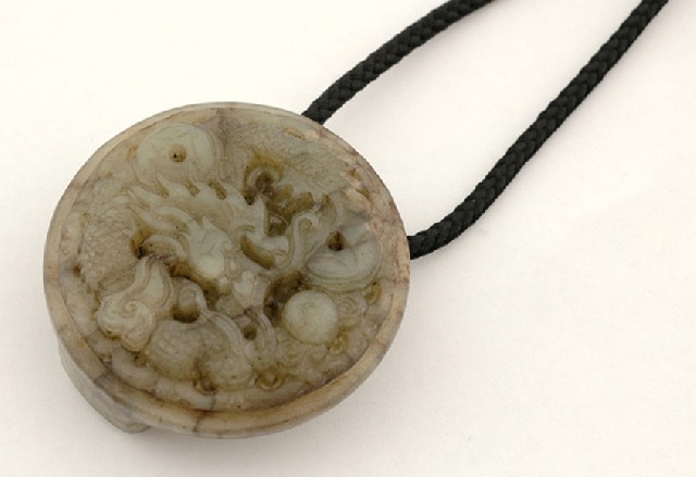 Appraisal: A serpentine pendant The intricately carved circluar pendant depicting a