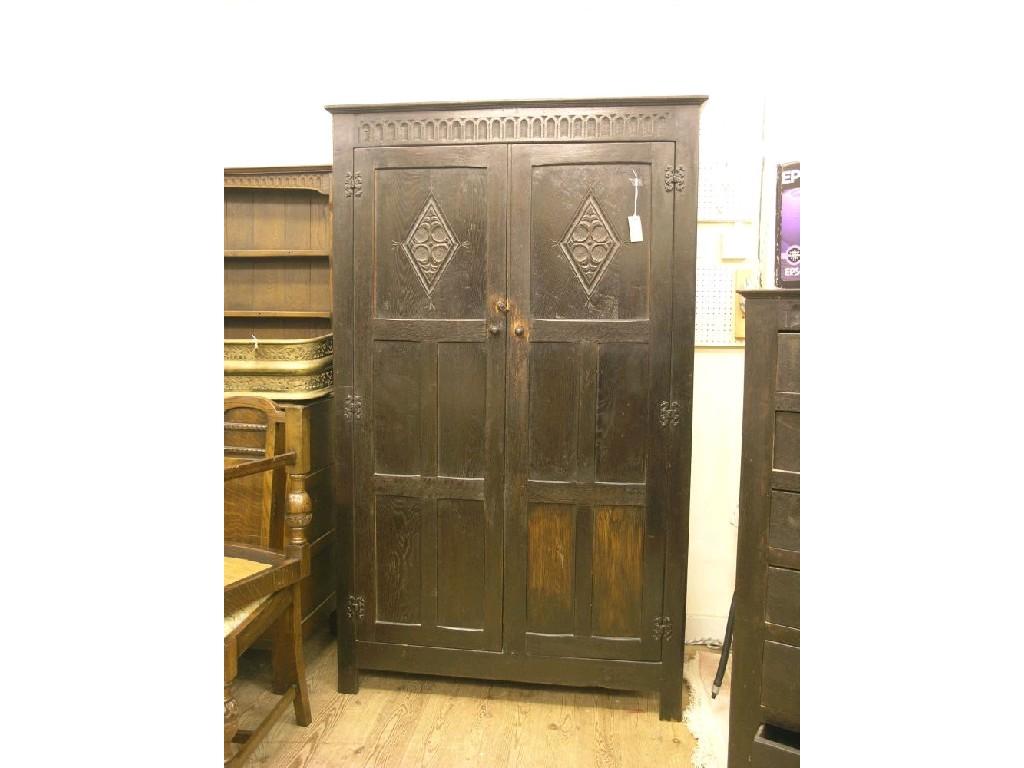 Appraisal: A dark oak wardrobe enclosed by a pair of full-length