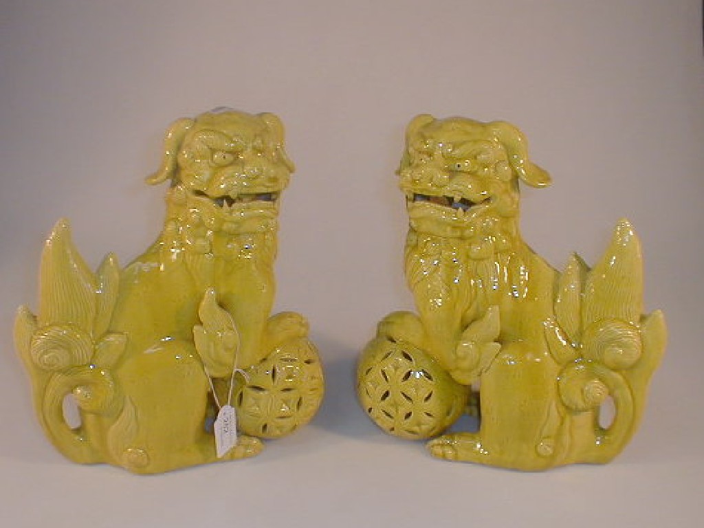 Appraisal: A pair of Chinese pottery temple dogs their foreleg resting