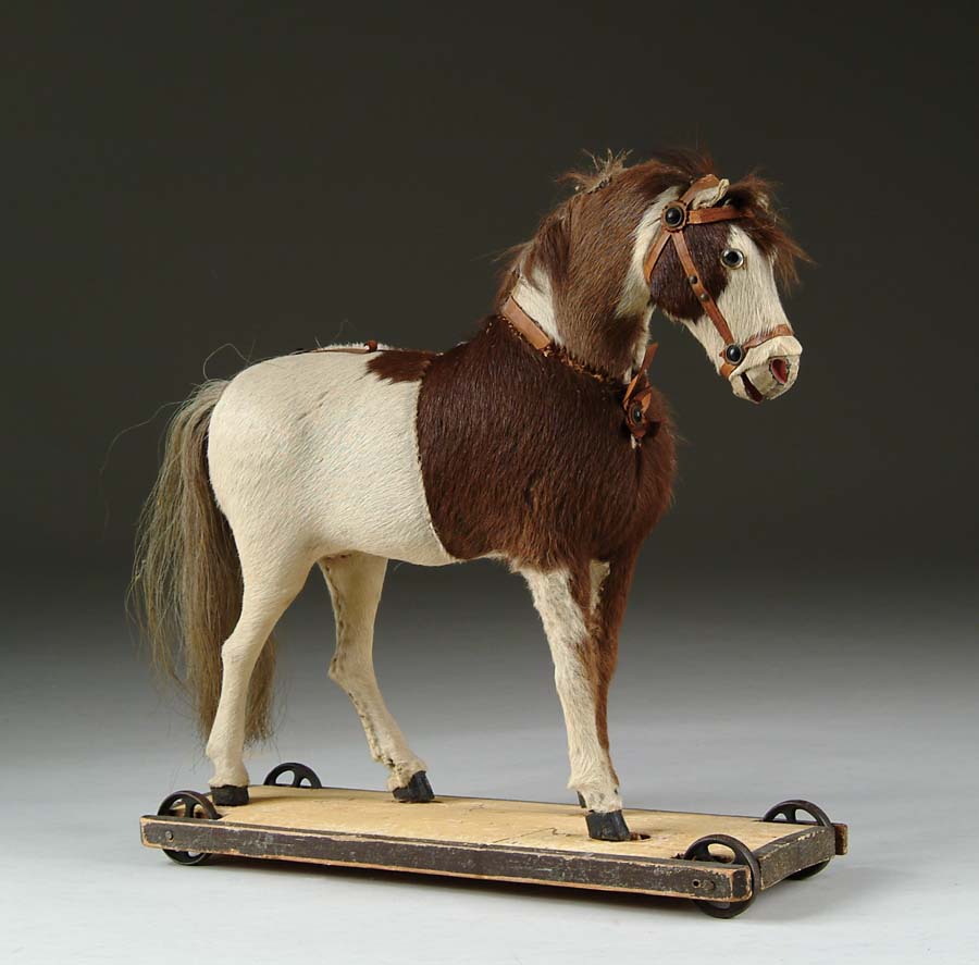 Appraisal: HIDE-COVERED HORSE ON WHEELED WOODEN BASE A palomino affixed atop