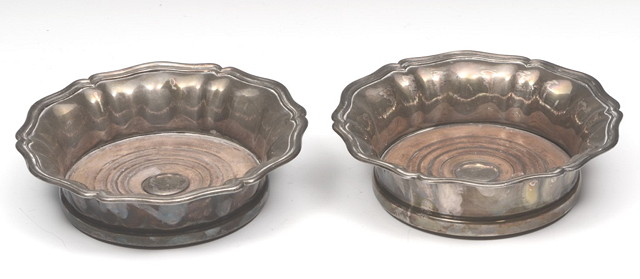 Appraisal: A PAIR OF SILVER PLATED BOTTLE COASTERS with shaped edge