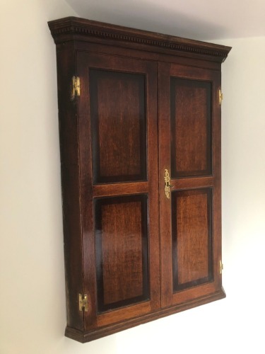 Appraisal: A George III oak hanging corner cupboard with dentil moulded