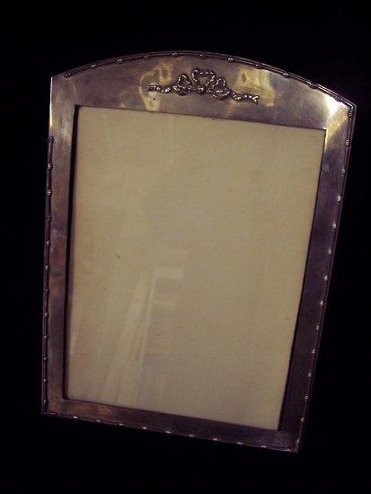 Appraisal: A silver photograph frame the arch top with embossed ribbon