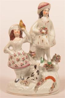 Appraisal: Staffordshire China Figurine Girl holding yellow bird man holding floral