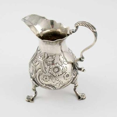 Appraisal: A George II pear-shaped embossed cream jug on three legs