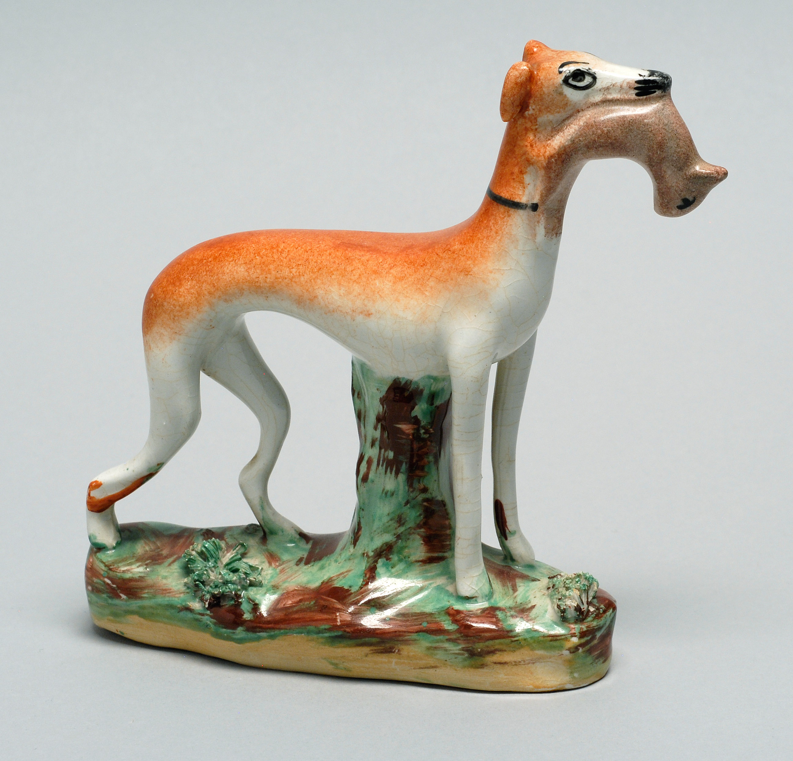 Appraisal: STAFFORDSHIRE WHIPPET FIGURE Last Half Mid CenturyOrange whippet holding a