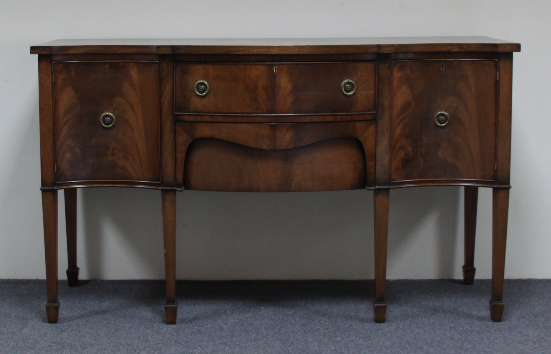 Appraisal: A mahogany serpentine front sideboard on square tapering legs with