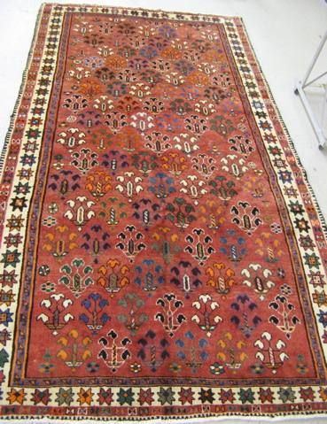 Appraisal: PERSIAN TRIBAL CARPET repeating stylized flower clusters on rose ground