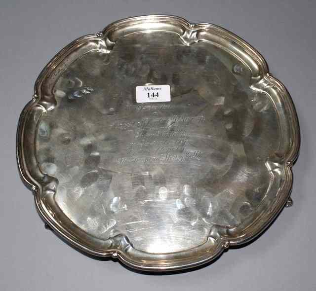 Appraisal: A CIRCULAR SILVER SALVER with scrolled border and standing on