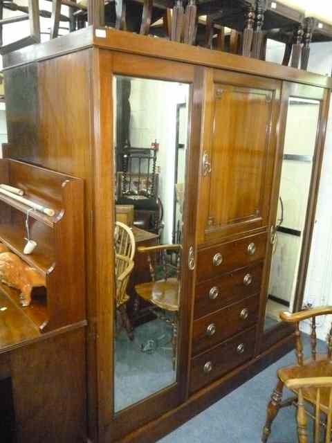 Appraisal: A MAHOGANY TRIPLE WARDROBE the central section with cupboard over