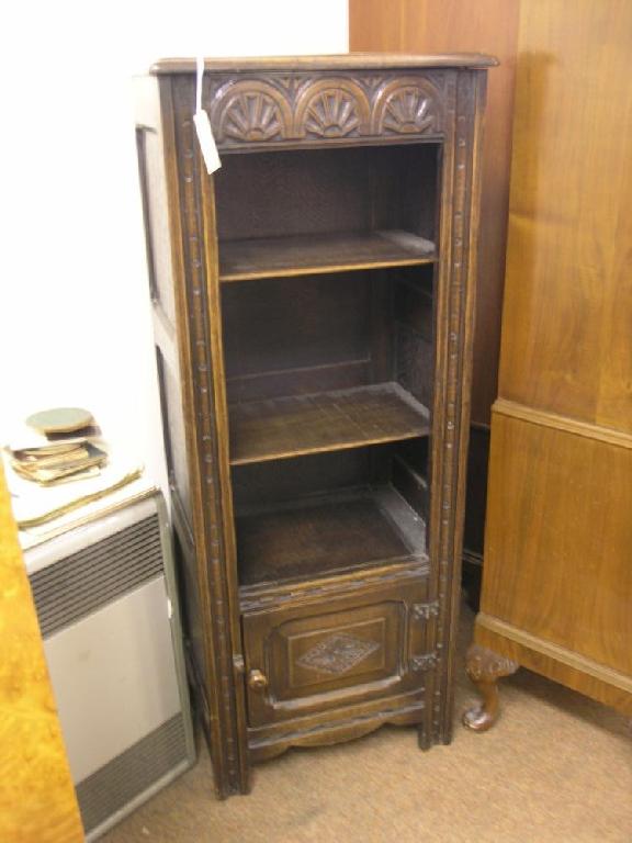 Appraisal: A narrow solid dark oak open bookcase with carved lunette