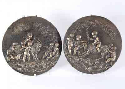 Appraisal: A silvered pair of cast metal roundels depicting putti on