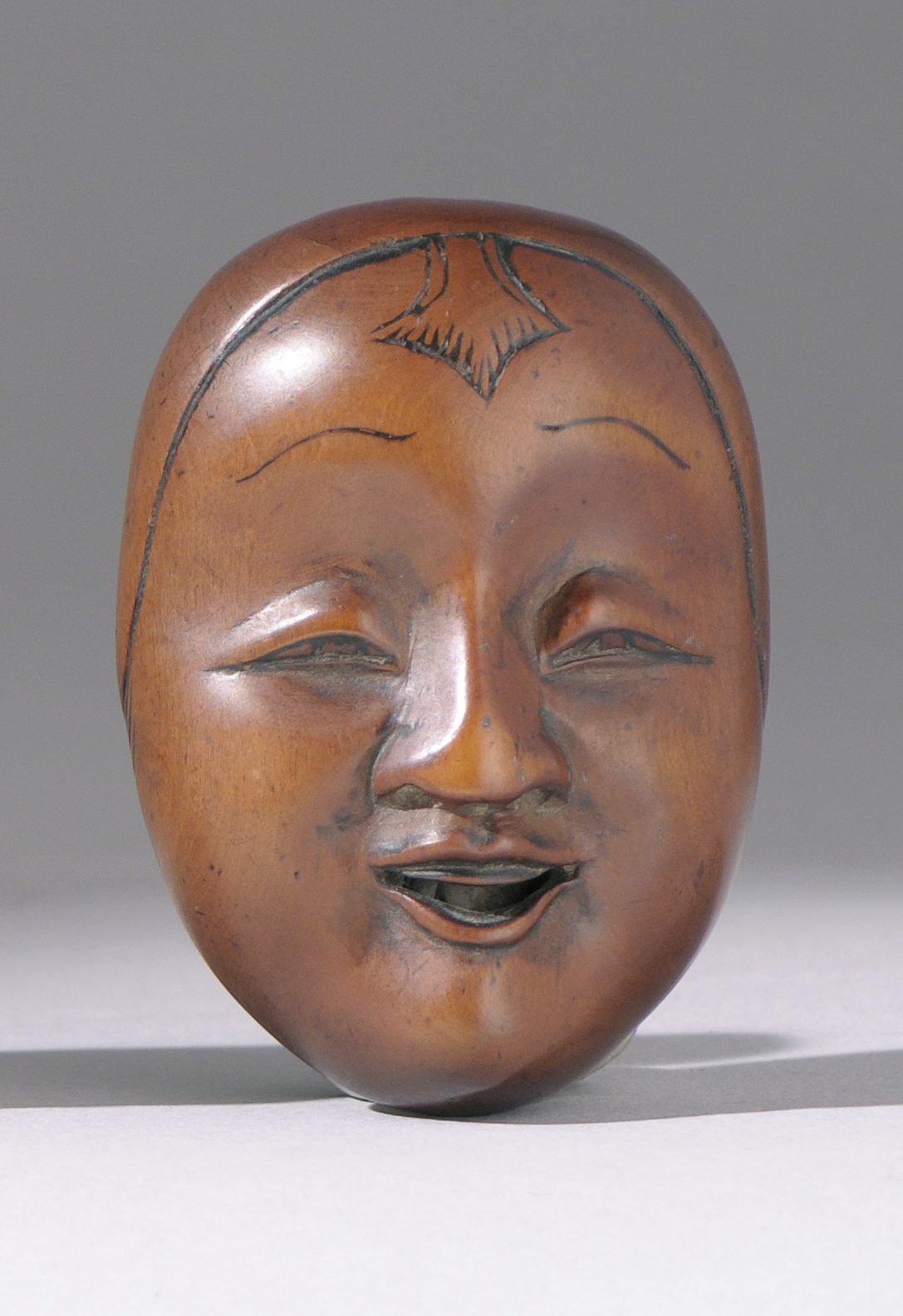 Appraisal: WOOD MASK NETSUKE Early th CenturyDepicting a smiling young woman