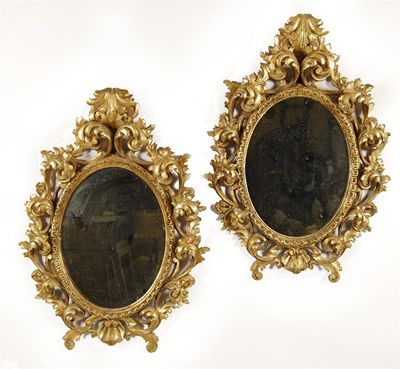 Appraisal: A pair of Florentine giltwood oval wall mirrors with ornate