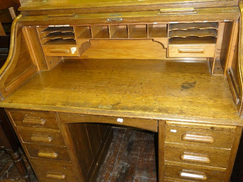 Appraisal: A late Victorian Edwardian oak roll top kneehole pedestal desk