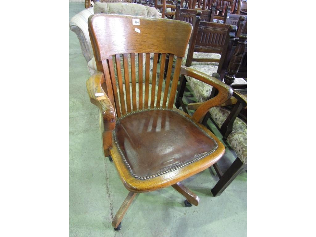 Appraisal: An Edwardian oak swivel office desk chair with rail back