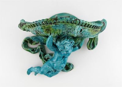 Appraisal: A Continental Majolica wall bracket modelled as a putti supporting