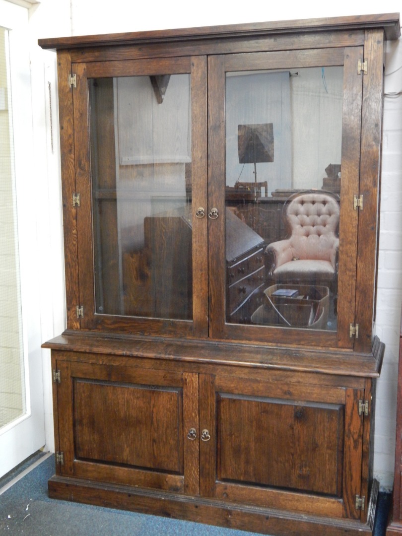 Appraisal: An oak cupboard bookcase the pediment over two glazed doors