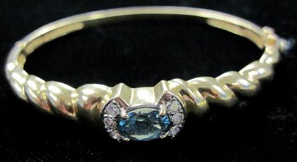 Appraisal: karat yellow gold bangle braceletAccented by an oval cut topaz