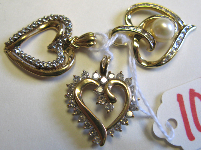 Appraisal: THREE DIAMOND AND GOLD OPEN HEART PENDANTS The lot includes