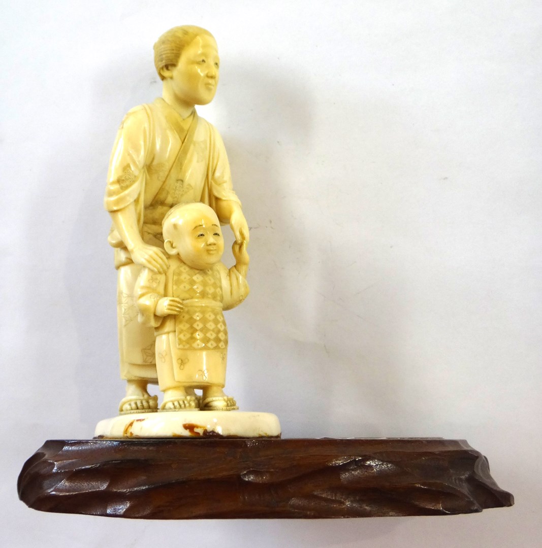 Appraisal: A Japanese ivory okimono of a woman helping a child