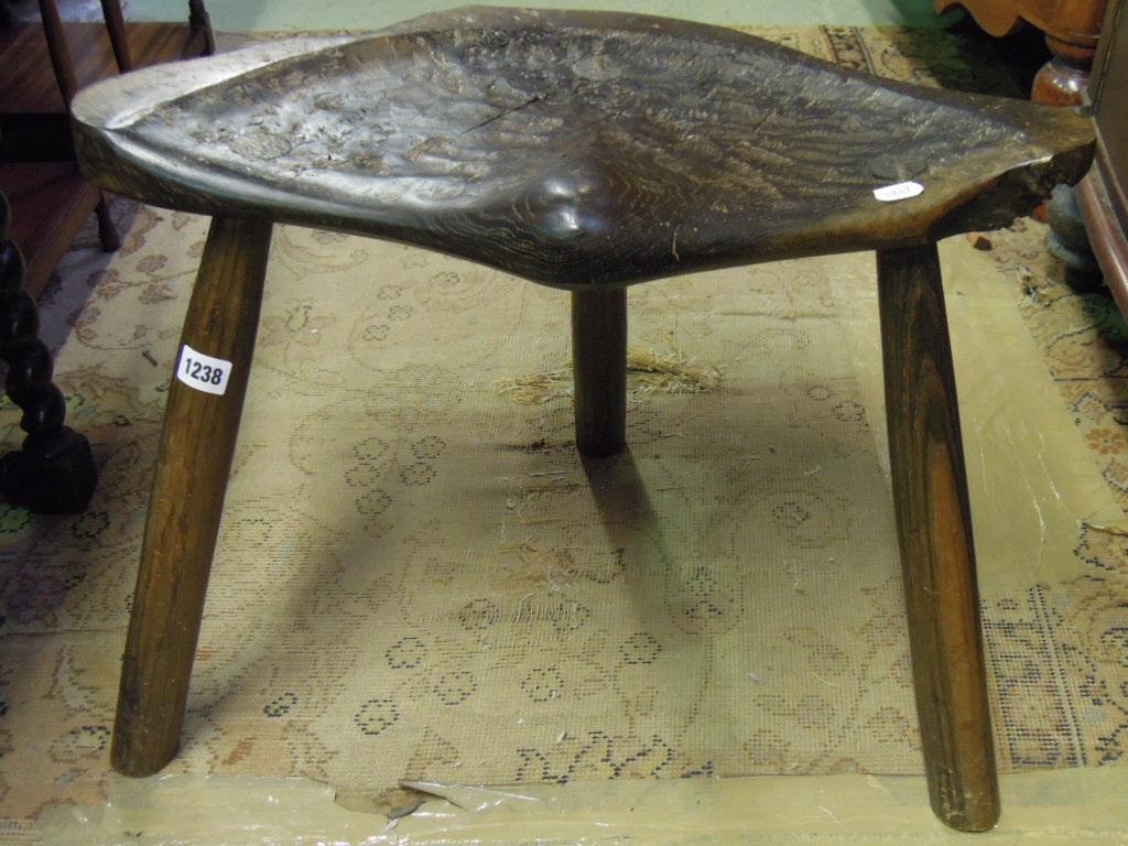 Appraisal: A rustic stool with stained burr oak saddle shaped seat