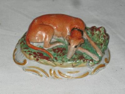 Appraisal: A STAFFORDSHIRE POTTERY GREYHOUND modelled lying on an oval green