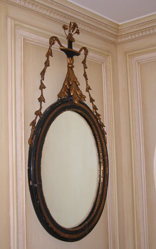 Appraisal: Title Pair Ebonized and gilded oval-shaped wall mirrors with vase